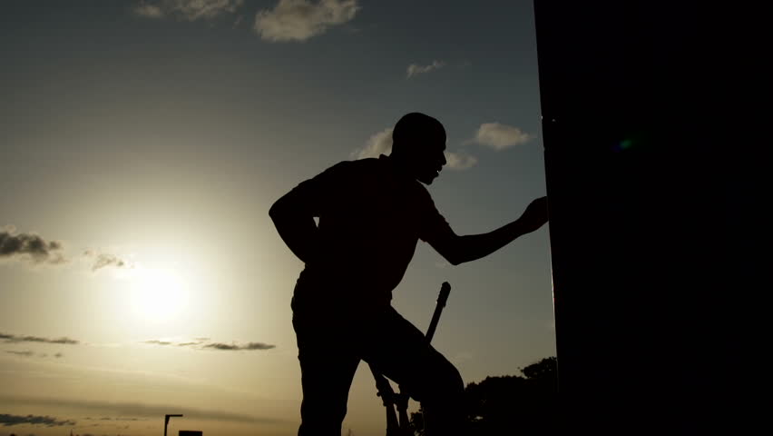 A man Silohuette opening a container with tongs. Sunset in the background.