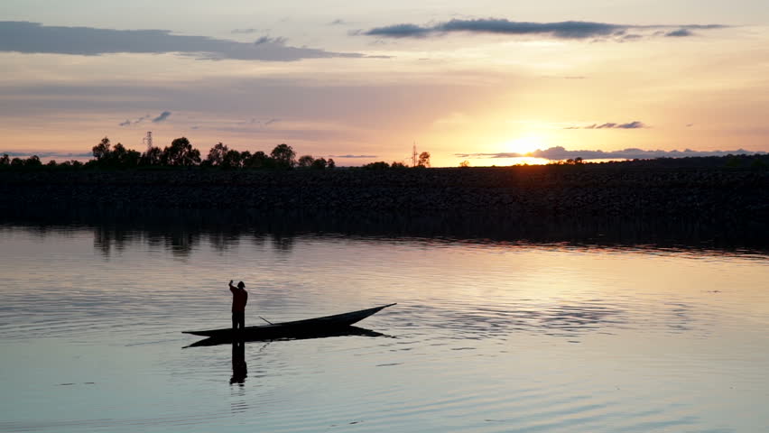 Silohuette of a fisherman fishing with a small canoe on a lake at sunset in Mali, Africa.
