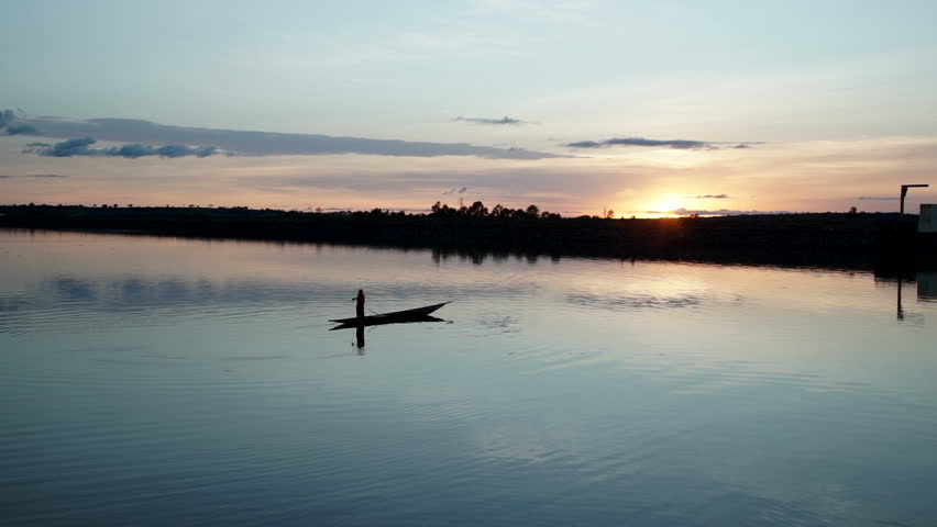 A fisherman fishing with a small canoe on a lake at sunset in Mali, Africa.
Silohuette