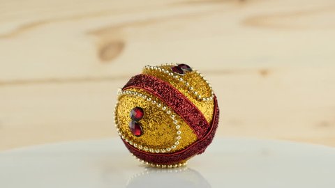 Gold red shiny New Year or Christmas ball on vintage wooden background, rotating 360 degrees, 4k