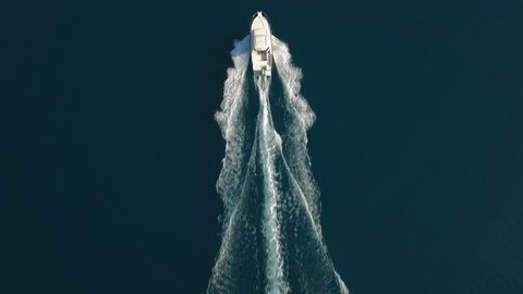 Aerial - Top down view of catching luxury motor boat racing on the water