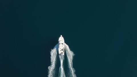 Aerial - Top down tracking shot of a bigger speed boat cruising on water