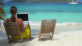 woman on laptop computer on tropical beach in the Caribbean