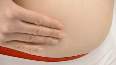 Woman is testing the skin of her stomach for the presence of stretch marks