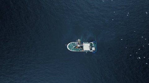 Zoom out of a Commercial Ship Fishing with Trawl Net on the Sea. Top down view. Shot on Phantom 4K UHD Camera.