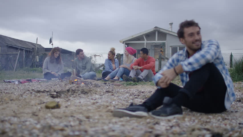 4K Friends with bonfire at the beach, portrait of young man smiling to camera (UK-Oct 2016)