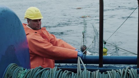 Fisherman Works on Commercial Fishing Ship that Pulls Trawl Net. Shot on RED Cinema Camera in 4K (UHD).