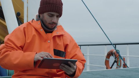 Casualy Dressed Fisherman Using Tablet Computer with Navigation Maps while Traveling on Ship. Shot on RED Cinema Camera in 4K (UHD).