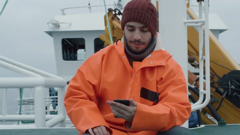 Casualy Dressed Fisherman Using Mobile Phone while Traveling on Ship. Shot on RED Cinema Camera in 4K (UHD).
