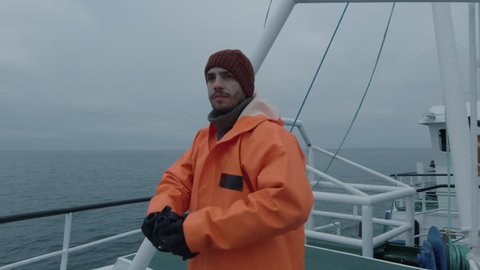 Captain of Commercial Fishing Ship Dressed in Protective Coat Looking through Binoculars. Shot on RED Cinema Camera in 4K (UHD).