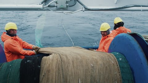 Team of Fishermen Unwind the Trawl Net during Commercial Fishing. Shot on RED Cinema Camera in 4K (UHD).
