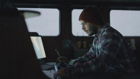 Captain Surrounded by Monitors and Screens with Sea Maps Pilots Commercial Fishing Ship. Shot on RED Cinema Camera in 4K (UHD).