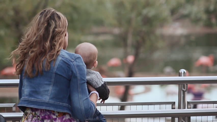Mother with baby in her arms on the bridge in the park.