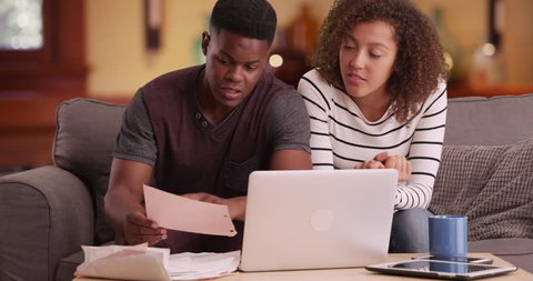 African American couple pays their bills on their laptop. Black millennial man and woman does their taxes online using computer. 4k.