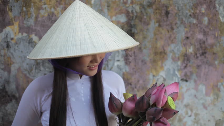 MH LD Young Woman Wearing Ao Dai and Straw Hat Holding Flowers / Hoi An, Vietnam