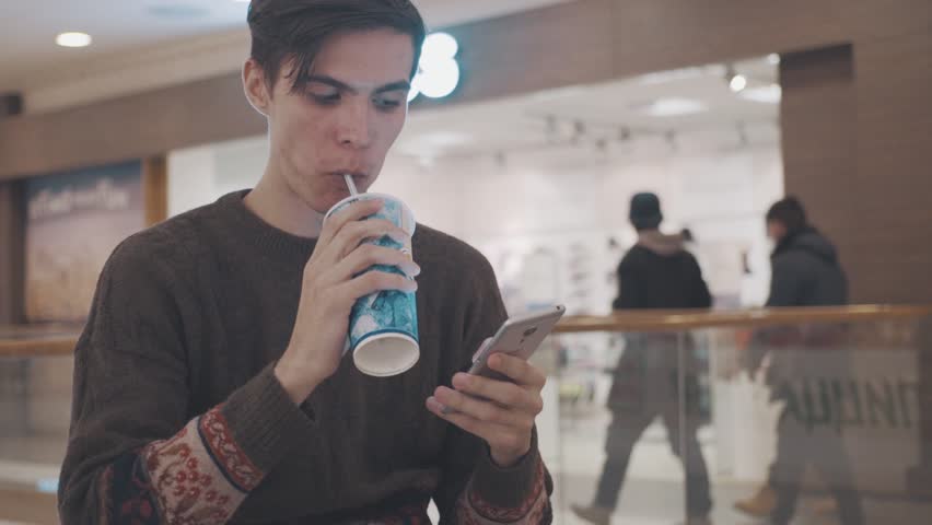 Young men using smartphone eat pizza and drink coke at shopping mall. Portrait Royalty-Free Stock Footage #21865705
