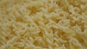 Slow tilt over raw corkscrew shaped pasta pile on table 4K 2160p 30fps UltraHD footage - Traditional Italian food background close-up 3840X2160 UHD tilting video