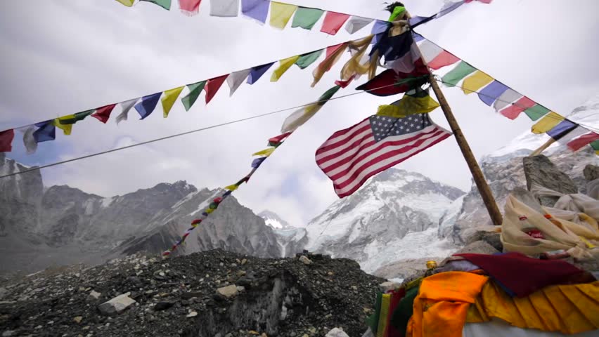 View of american and prayer flags waving on wind in Everest base camp, situated on Khumbu Icefall and is visited by thousands of trekkers each year. Himalaya, Nepal