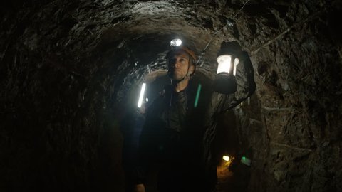 4K Team of potholers with hard hats and lamps exploring underground cave system. (UK-Oct 2016)