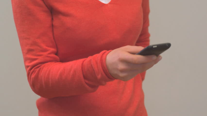 MEDIUM CLOSE UP PAN OF A WOMAN USING A CELL PHONE ON WHITE BACKGROUND