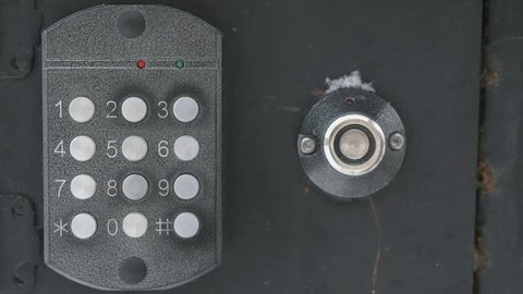 Person's hand dials the number of the apartment on the old panel of intercom system outdoors