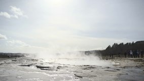 Lockdown shot of tourists watching Strokkur geyser erupting in Iceland
