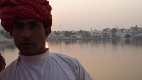Handheld, Good looking Rajasthani couple in ethnic wear taking photos from a mobile phone camera with sunset at the Pushkar Lake, India