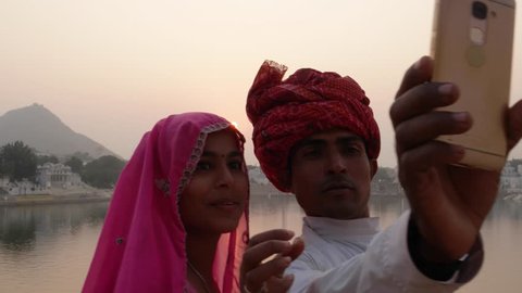 Handheld, Rajasthani couple taking selfies from a mobile phone camera at the Pushkar Lake, India