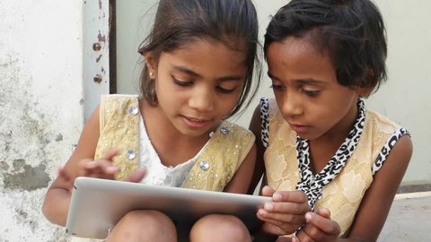 Kids busy working on a touch screen tablet and discussing, India