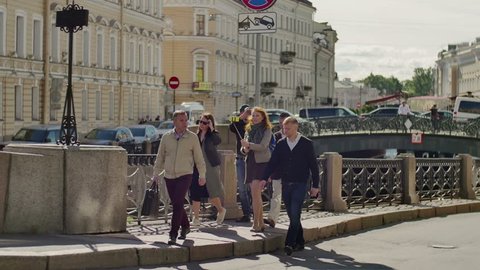 Tourist group with guide move along river embankment on background of historical city center