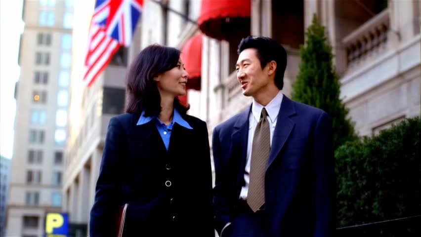 Asian business couple walking together downtown