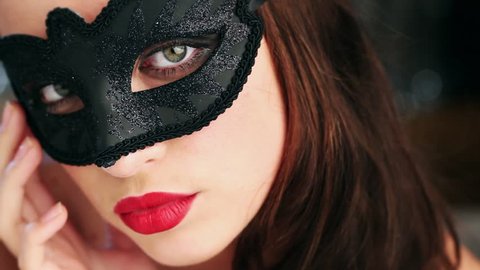 Sexy woman wearing masquerade mask stroking her neck flirting at party