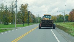 Tractor rides on the road slowly, prevents drive car. New York State, USA A typical area