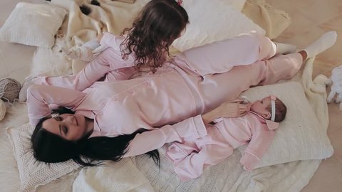 Mother and daughter with newborn baby in pink pajamas pajamas on Christmas Eve