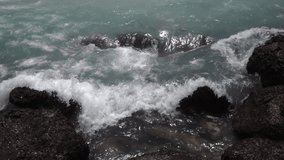 Slow motion, 240fps, of sea swash between boulders. Relax view of water stream, foam, splash and textured rocks. Beautiful background for amazing intro in full HD clip with eight times deceleration.