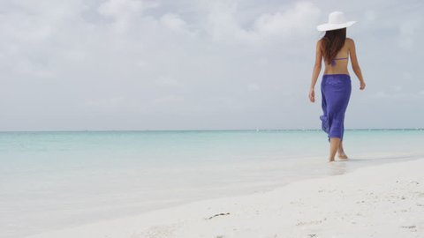 Woman in walking at tropical beach in sunshine. Perfect paradise beach.