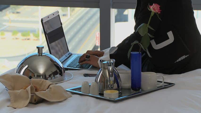 MEDIUM SHOT PAN OF A BUSINESSWOMAN ANSWERING HER CELL PHONE IN HER HOTEL ROOM