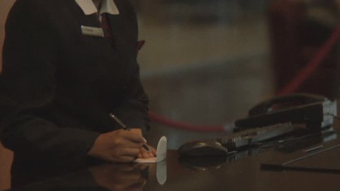 CLOSE UP OF A BUSINESSMAN CHECKING IN AT A RECEPTION DESK