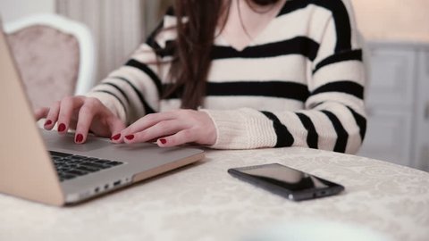 closeup hands of young woman uses laptop in a bright dining.