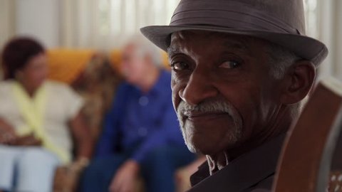 Portrait of elderly black man looking at camera. Group of friends in retirement home. Old people in medical clinic. Patients relaxing in hospice for seniors. Slow motion
