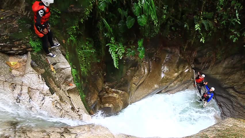 footage of a person jumping into a waterfall with sound. locked down, wide angle