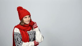 Christmas girl, young beautiful smiling wearing red knit hat and scarf looking to the side at blank copy space, and showing thumb up gesture at the end