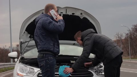 Two young men trying to repair the car.