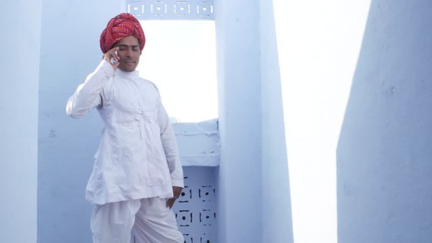 Confident dude on mobile phone cell ends call and poses for camera with hands on his waist in Pushkar, Rajsthan, India