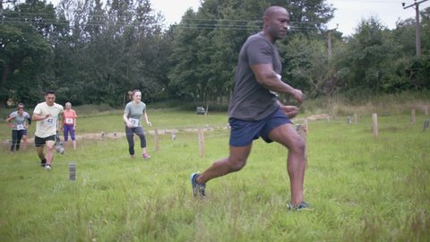 4K Competitors in assault course race running and crawling under net on ground (UK-Oct 2016)