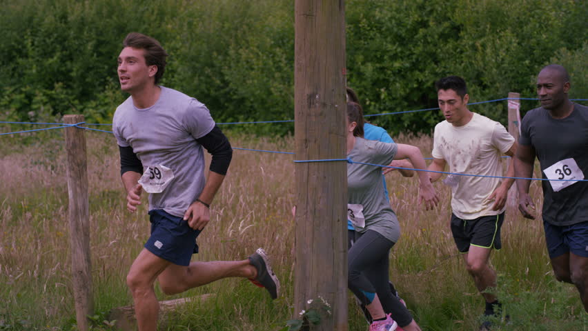 4K Muddy competitors climbing monkey bars at endurance sports contest (UK-Oct 2016)