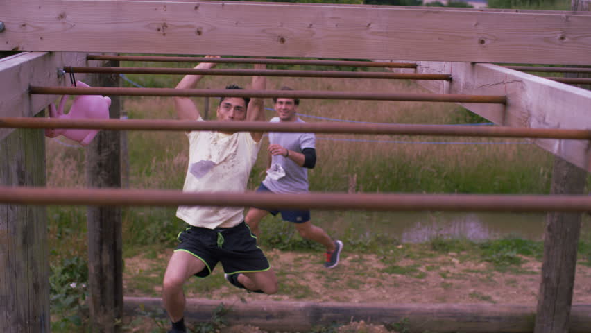 4K Muddy competitors climbing monkey bars at endurance sports contest (UK-Oct 2016)