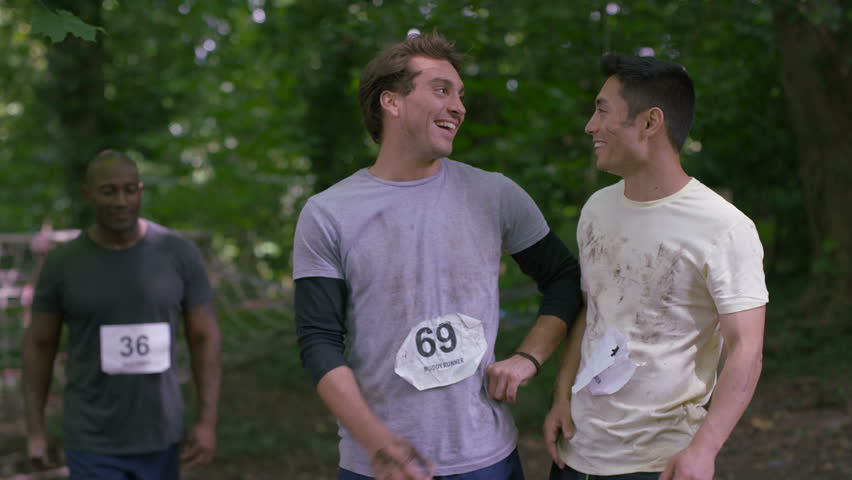 4K Portrait smiling male team competing in muddy endurance contest (UK-Oct 2016)