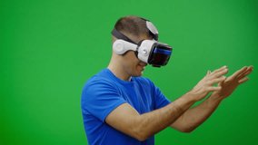 Man in a virtual reality mask observing digital video game world. Green screen.