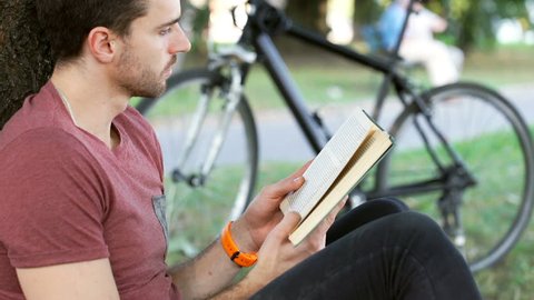 Man looking absorbed while reading book in the park, steadycam shot
